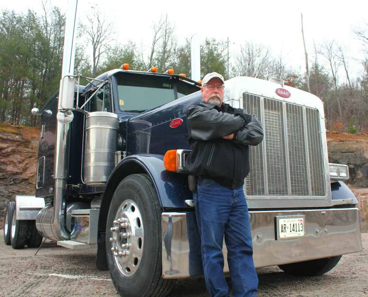 Experienced Veteran Truck Driver Smart Trucking Leaning on 379 Peterbilt