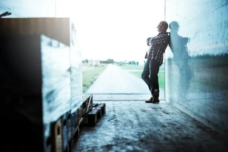 trucker in van trailer leaning with arms folded