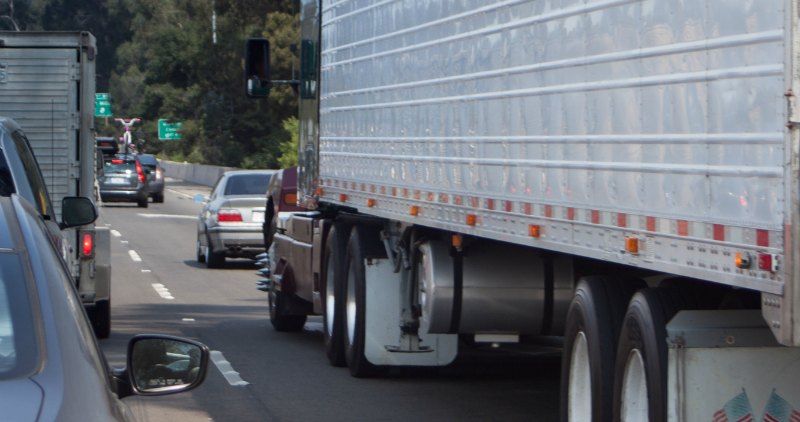 A photo of the lower-side of the truck as it drives along a highway with other vehicles. The truck's underside, with it's wheels and auxiliary fuel tank, can be seen clearly.