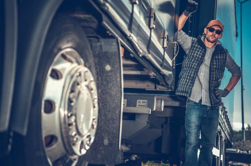 Truck driver leaning on big rig truck