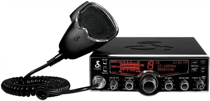 A photo of a Top Trucker CB Radio. It is a black box with a red display and lots of dials. There's also a microphone receiver attached by flexible wire. 