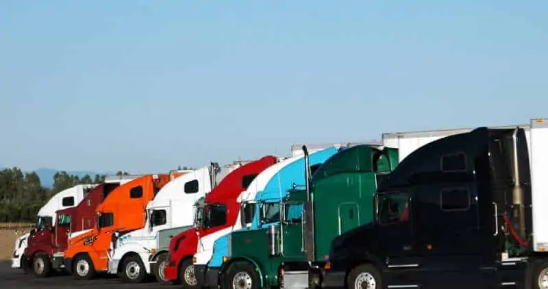 Row of coloured semi trucks with blue sky background during freight shortage 2023.