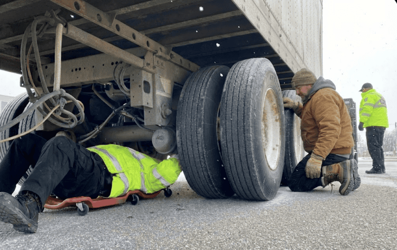 MTO officers inspecting a truck and a driver looking on.