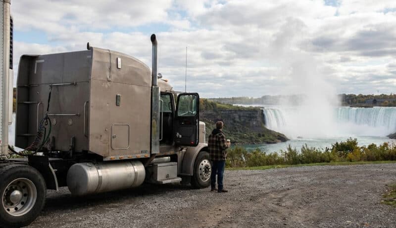 Truck driver standing beside his semi truck viewing NIagara Falls Canada